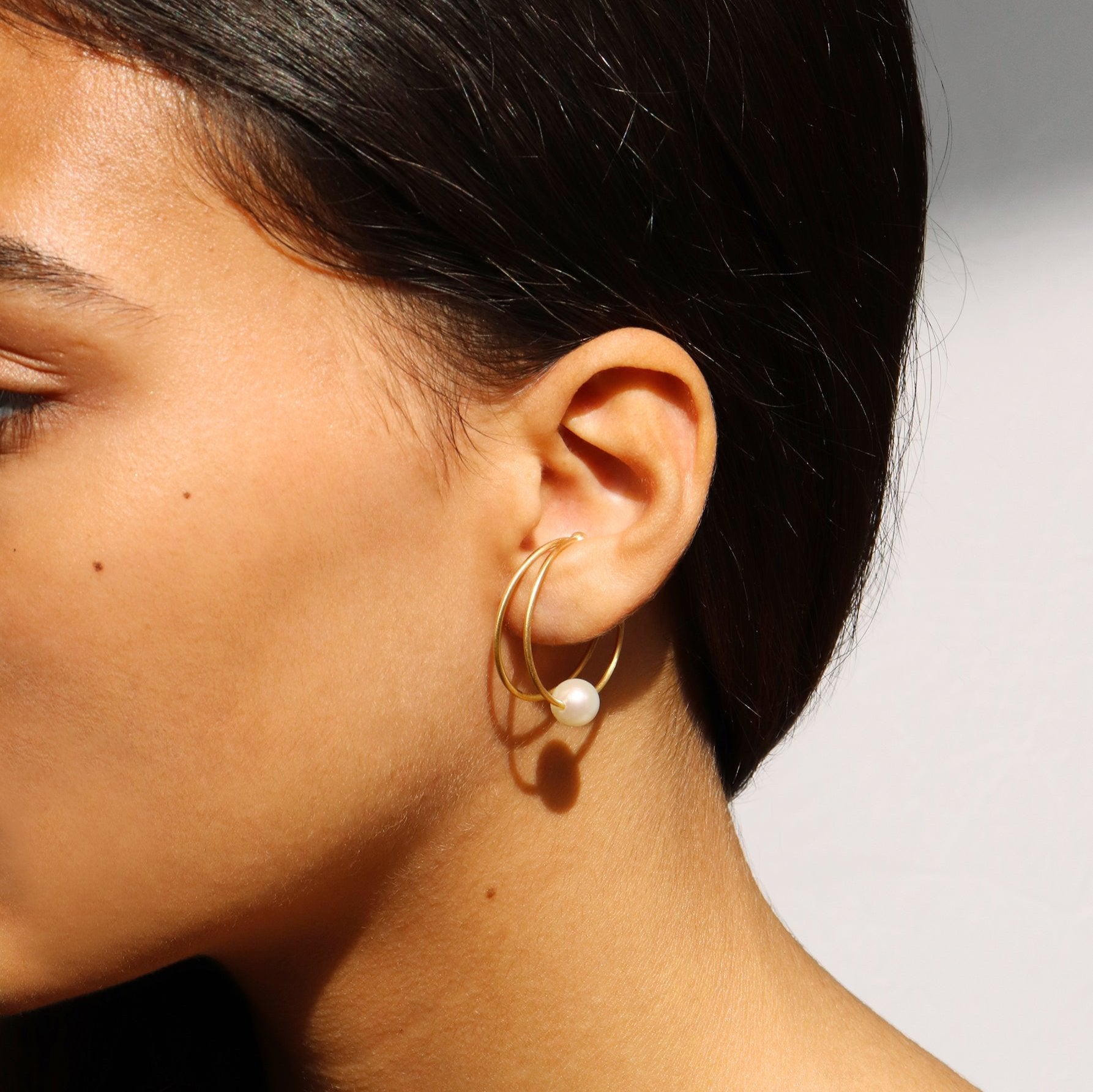 18KT yellow gold earring ear cuff with pearl worn by a female ear - Doppio Cerchio