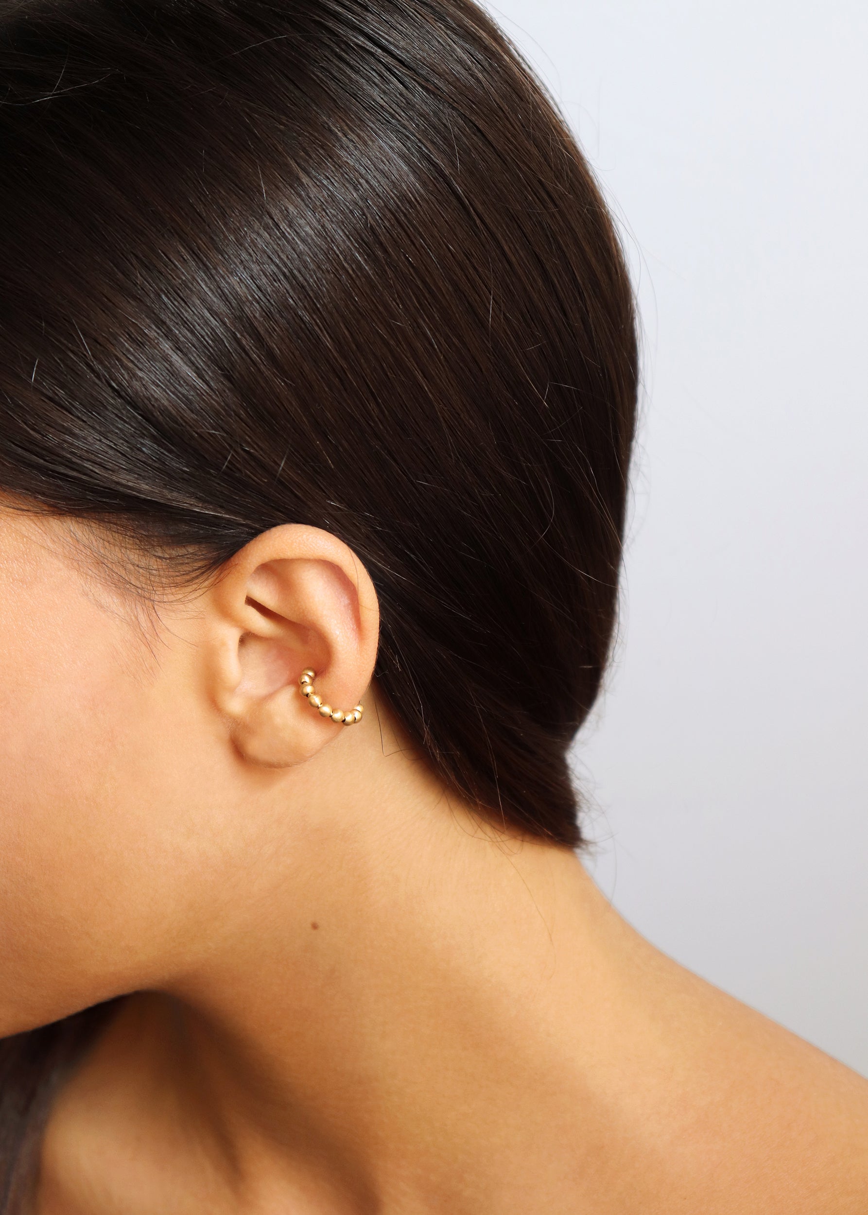 18KT yellow gold earring ear cuff worn by a female ear - Sfere