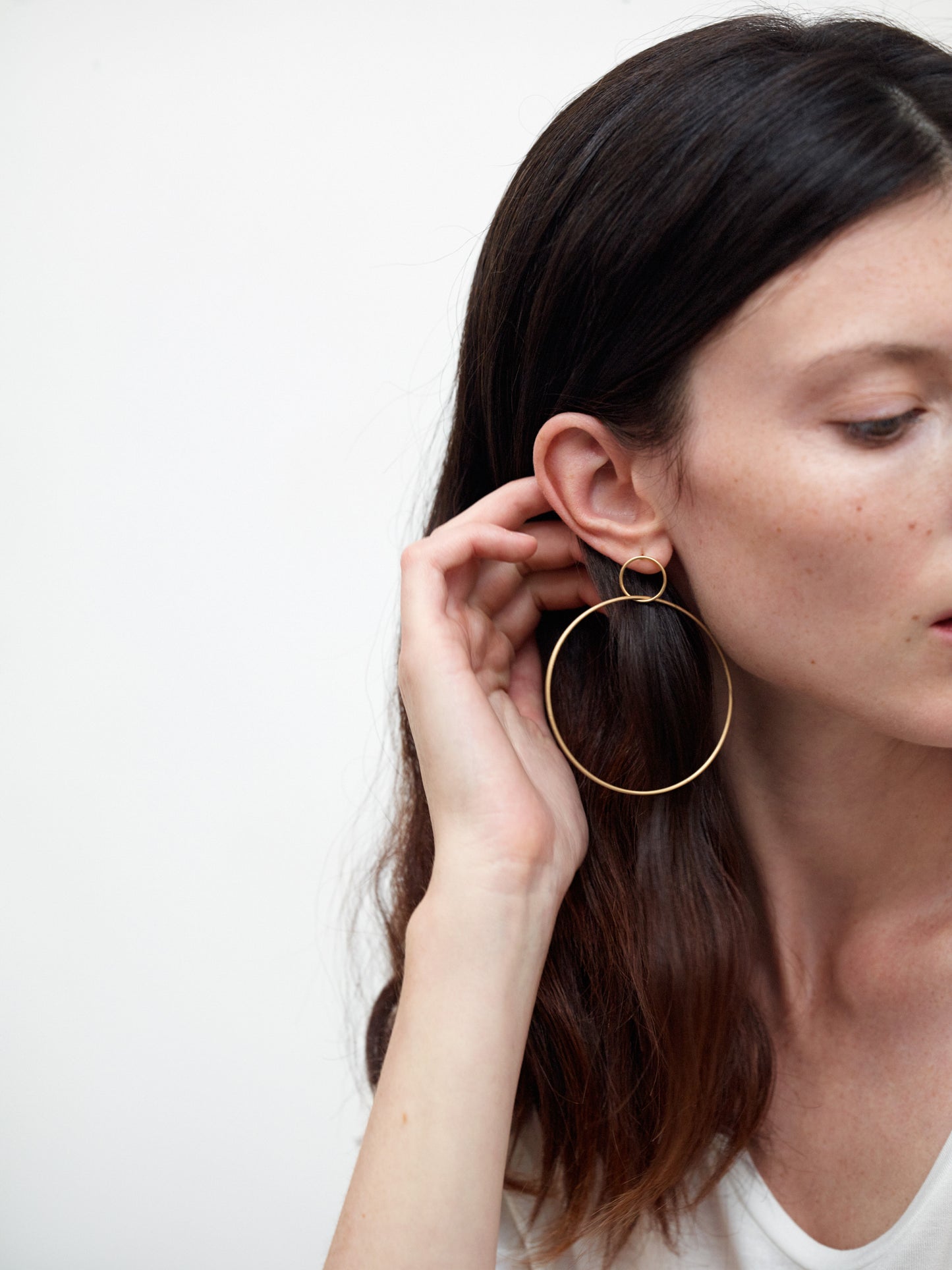 18KT yellow gold large hoop earrings worn by a female ear  - Grande Cerchio