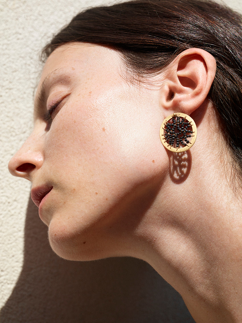 18KT yellow gold stud earrings with black diamonds worn by a female ear - Round Frame