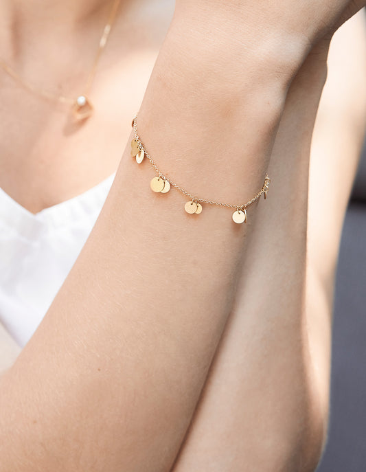 18KT yellow gold bracelet with pendants worn by a female hand  - Pianino B