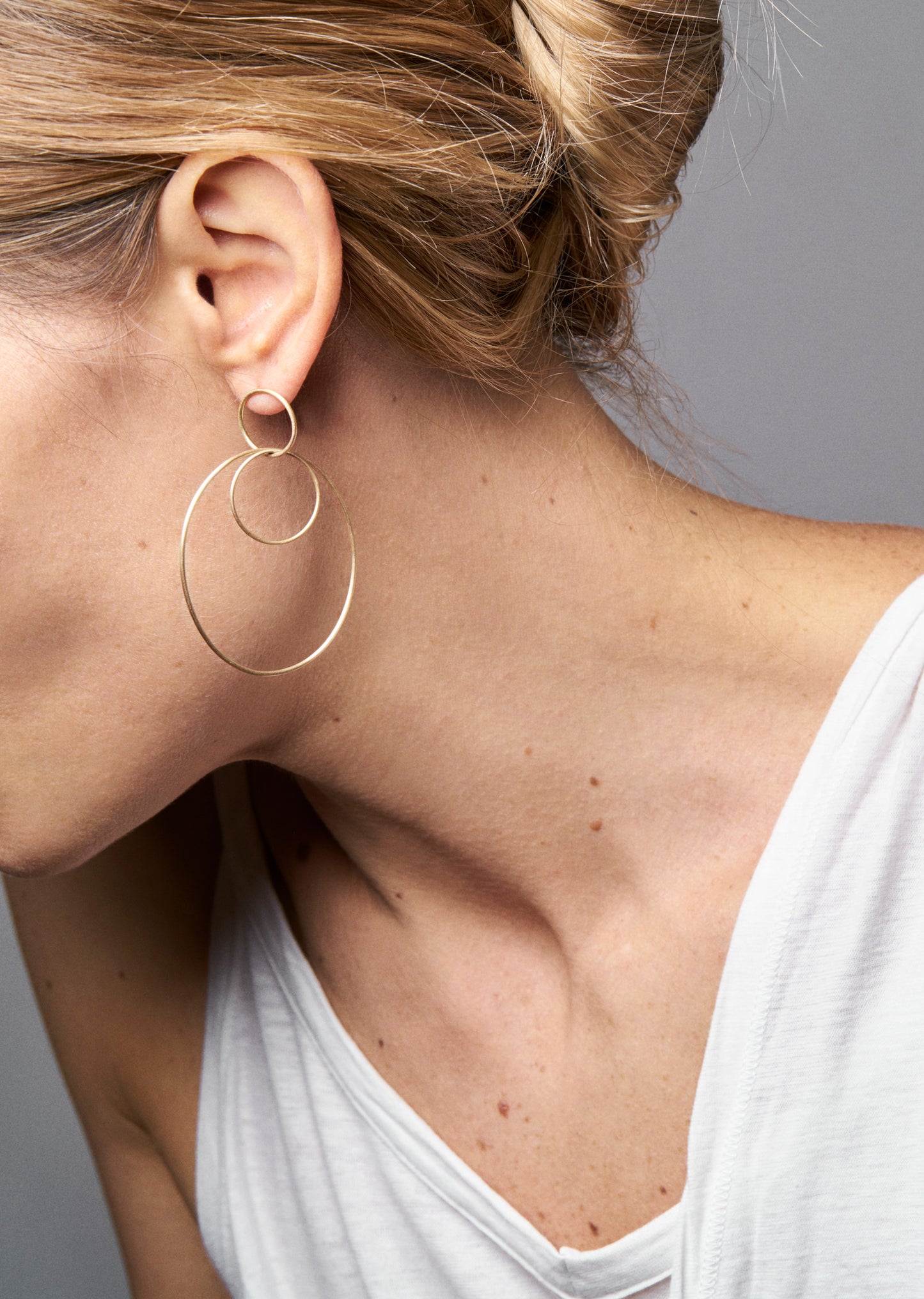 18KT yellow gold large hoop earrings worn by a female ear - Grande Ovale