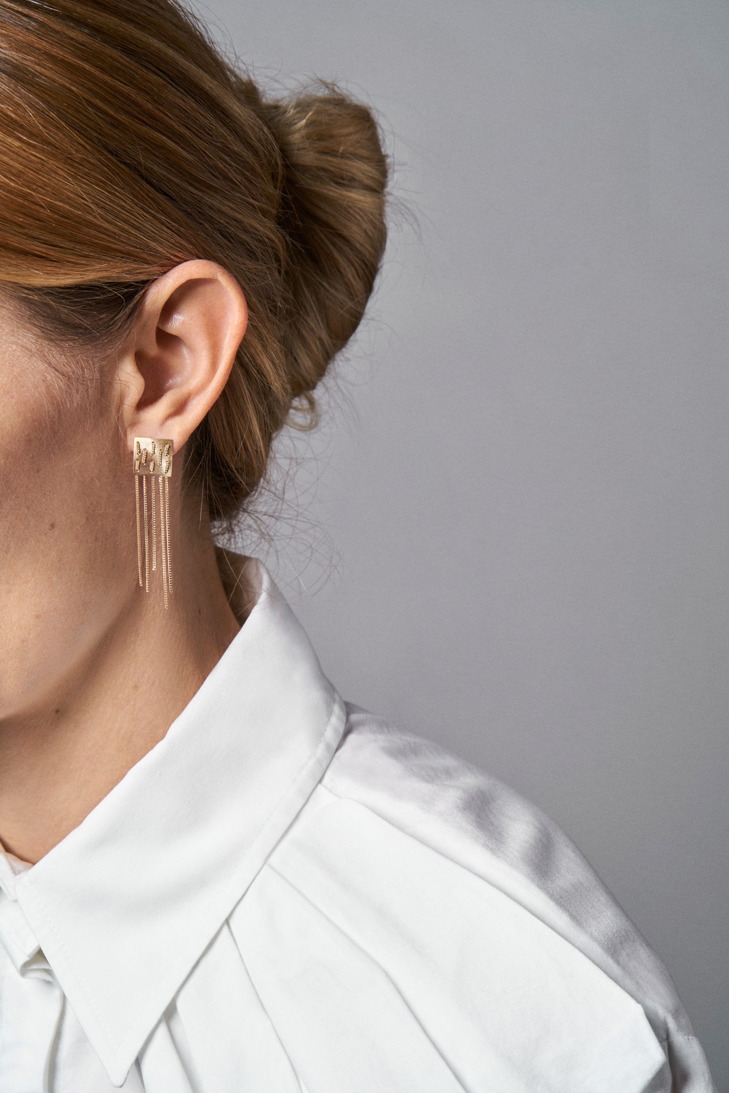 18KT yellow gold chained earrings worn by a female ear - Weave E