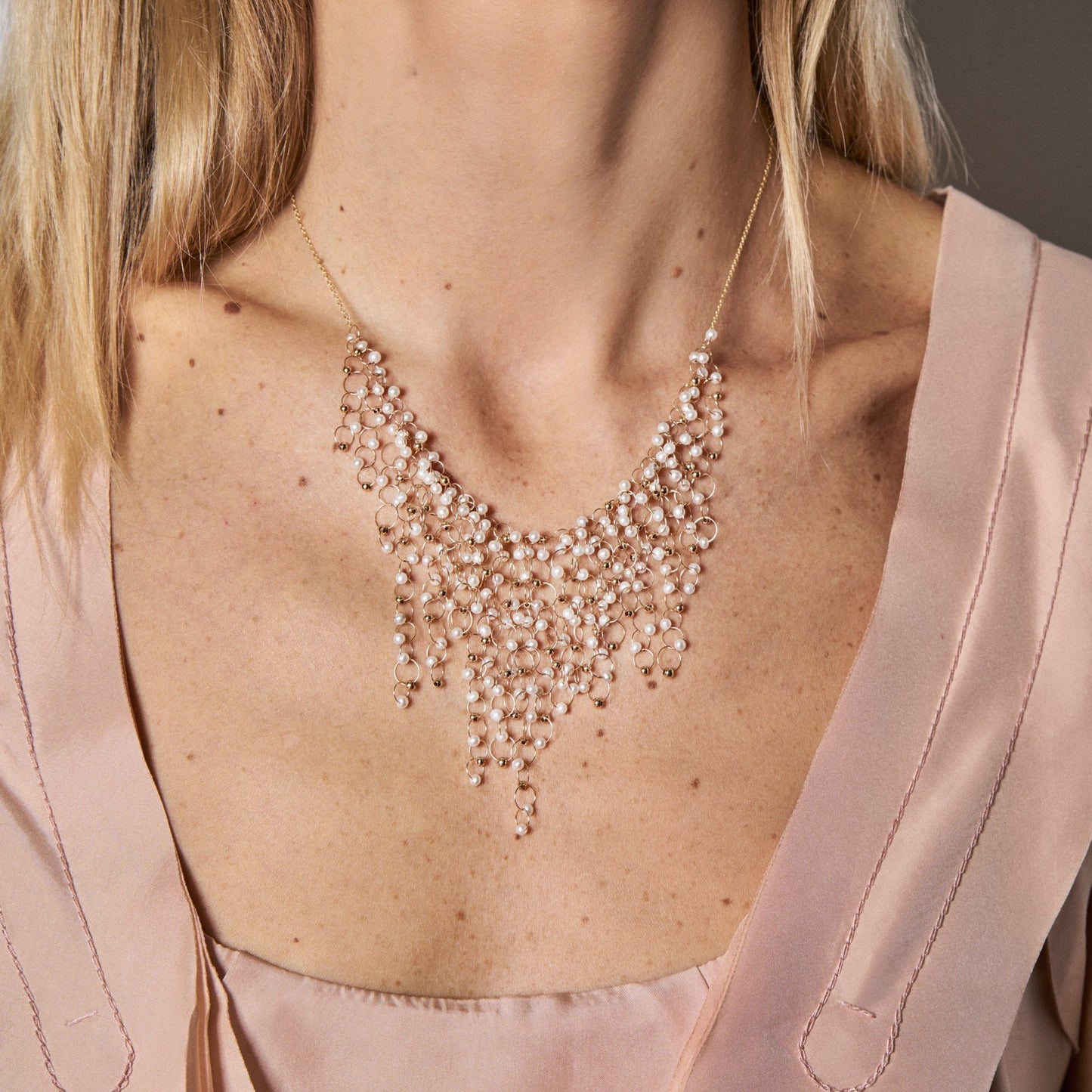 18KT yellow gold necklace with freshwater pearls worn by a female neck - Infinito N