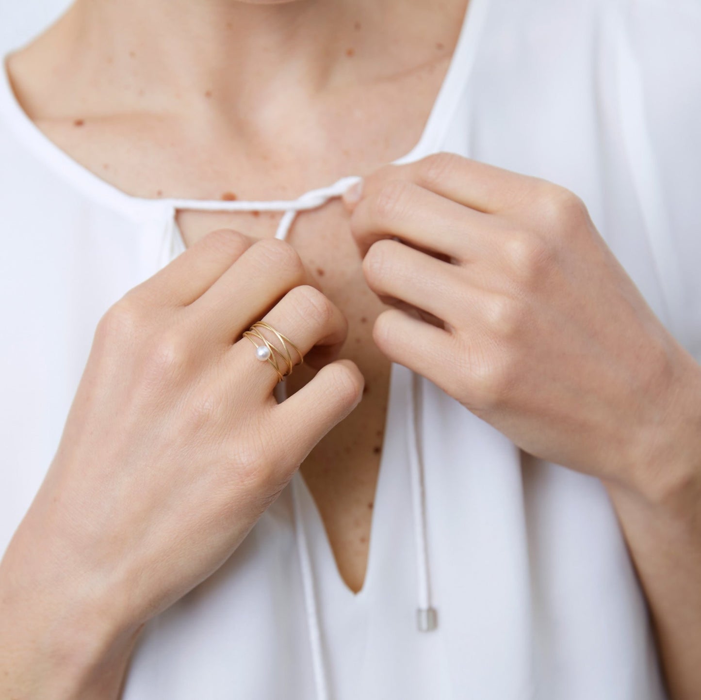 18KT yellow gold ring with white akoya pearl worn by a female hand - Cinque Cerchi