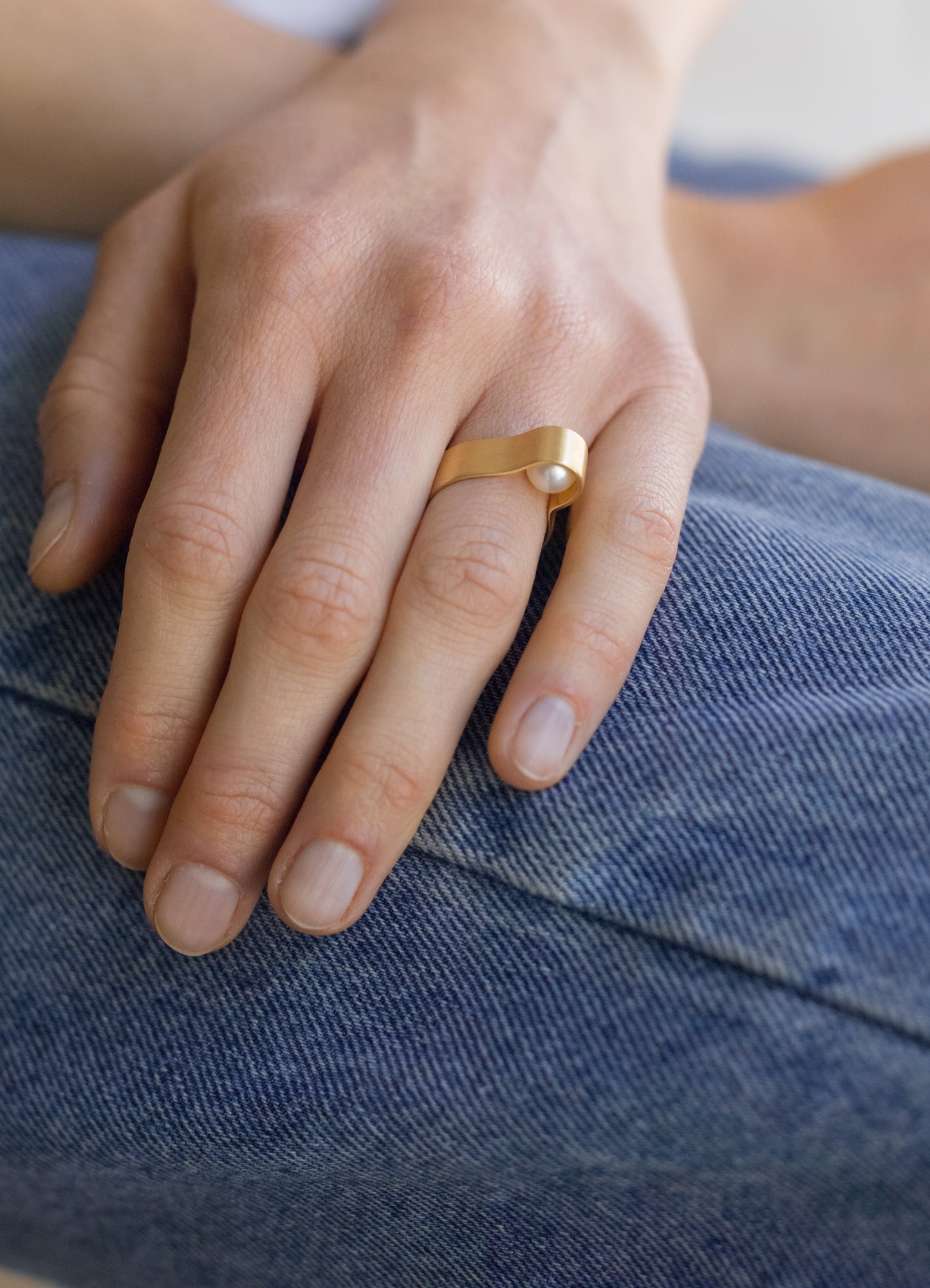 18KT white gold band ring with hidden akoya pearl (diameter 7,3 MM) worn by a female hand  – Wave