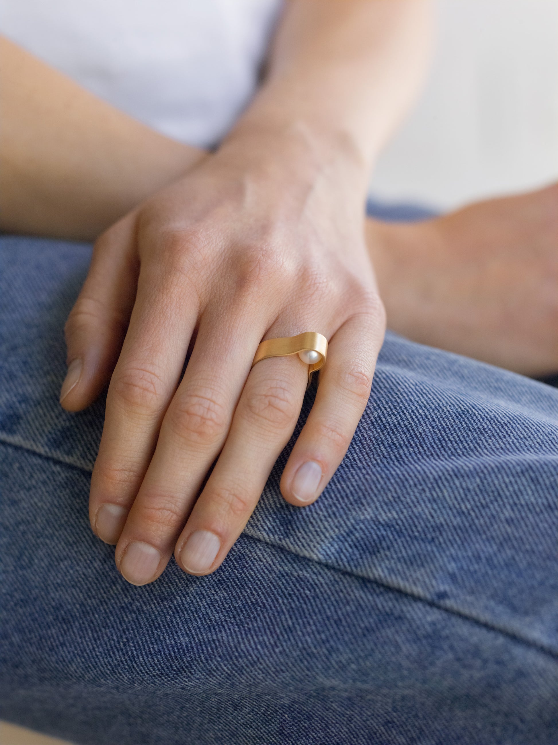 18KT white gold band ring with hidden akoya pearl (diameter 7,3 MM) worn by a female hand – Wave