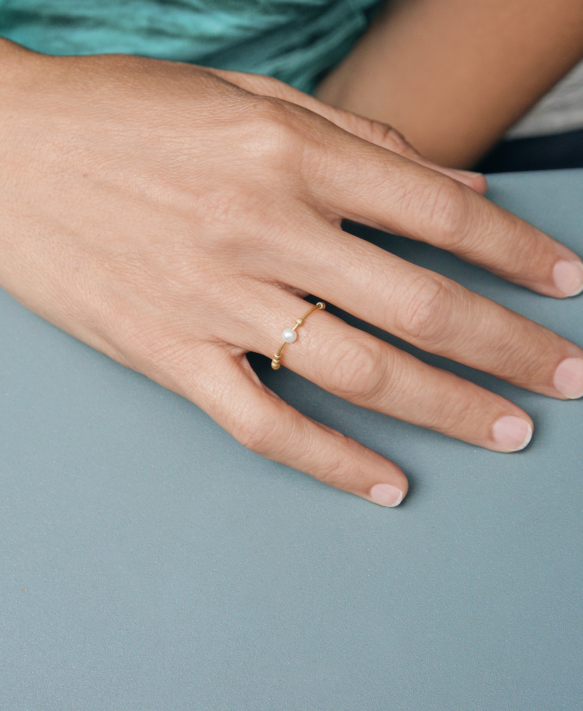 18KT thin yellow gold ring with gold spheres and freshwater pearl worn by a female hand - Toi Perla Oro