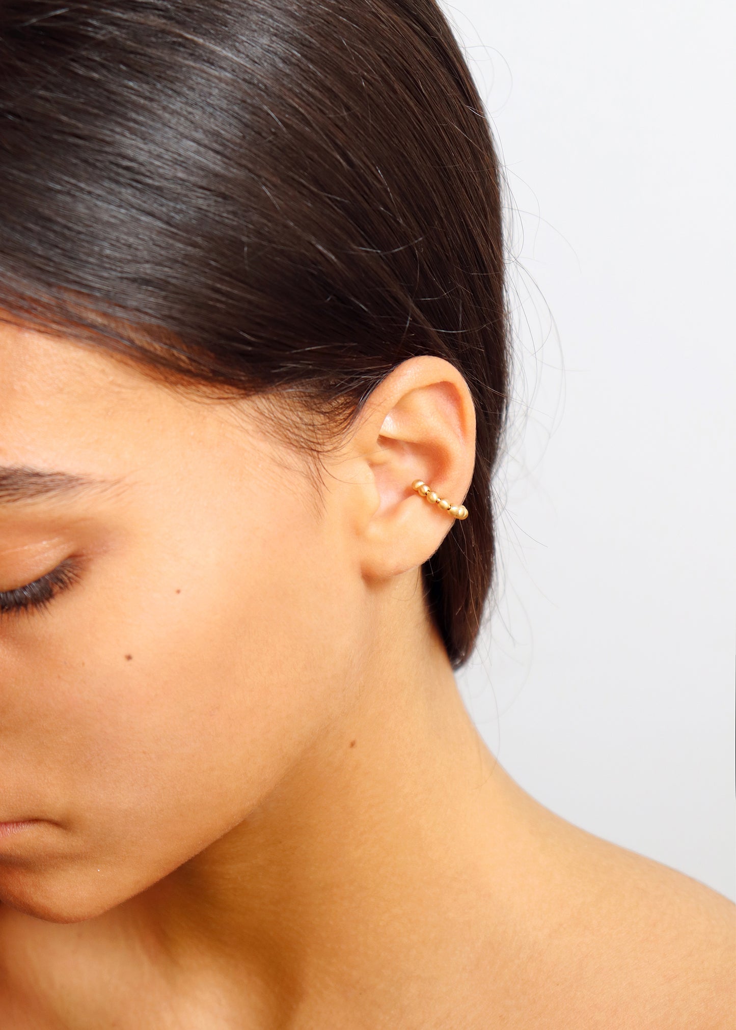18KT yellow gold earring ear cuff worn by a female ear - Sfere