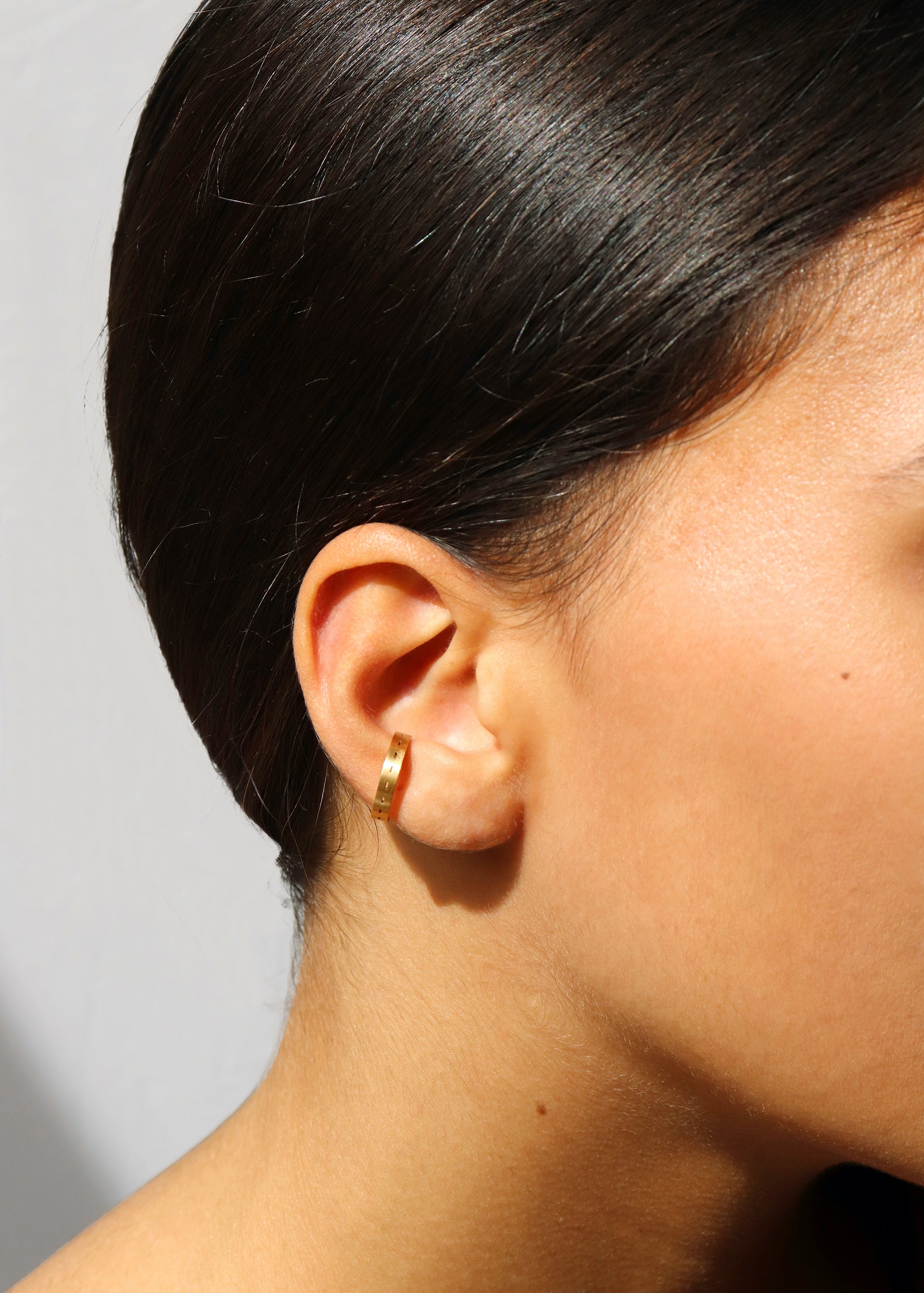 18KT yellow gold earring ear cuff worn by a female ear - Tratti 