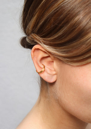 18KT yellow gold earring ear cuff worn by a female ear - Tratti 