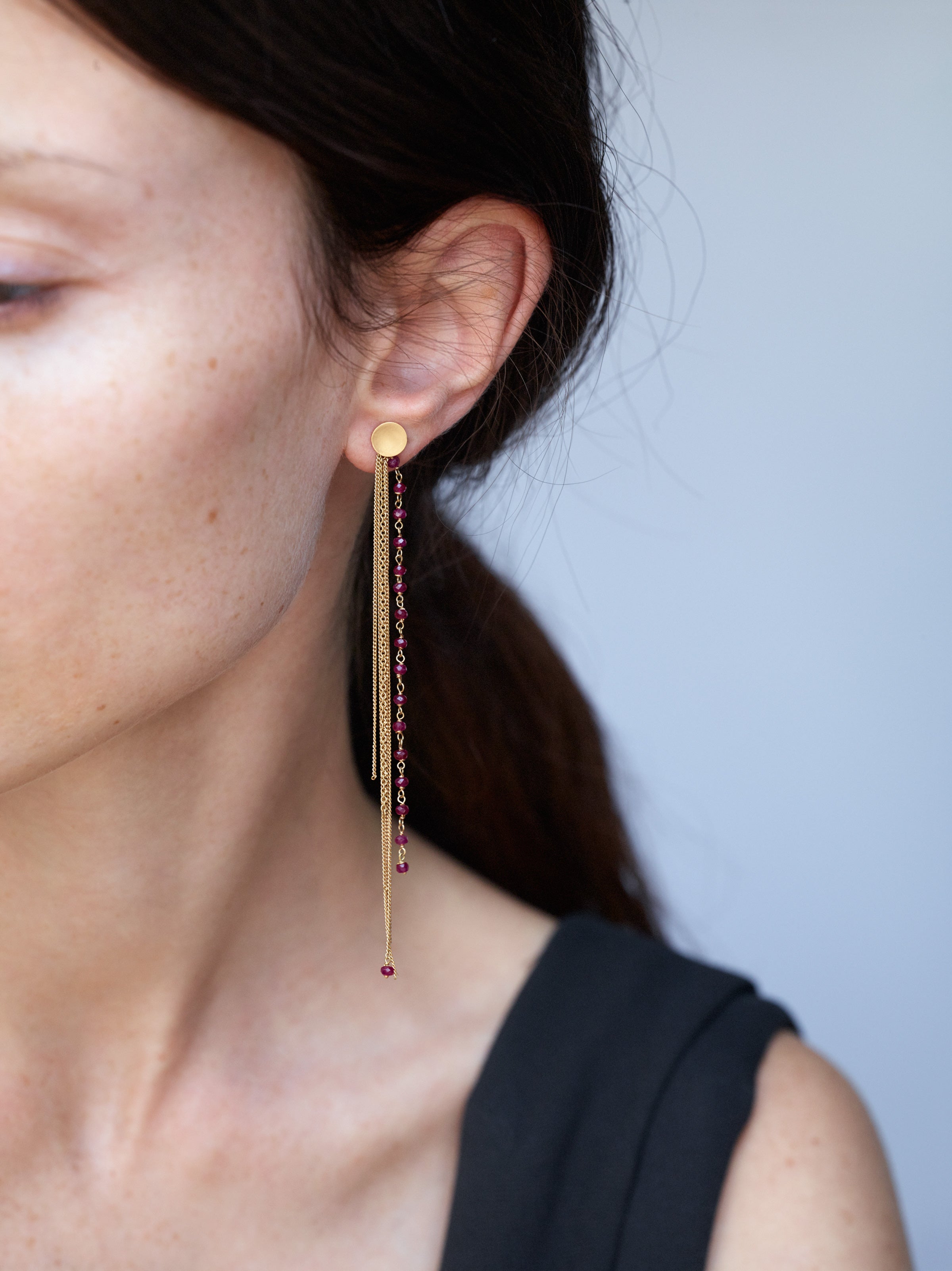 18KT fringe earrings in yellow gold with rubies worn by a female ear - Frange Rubino