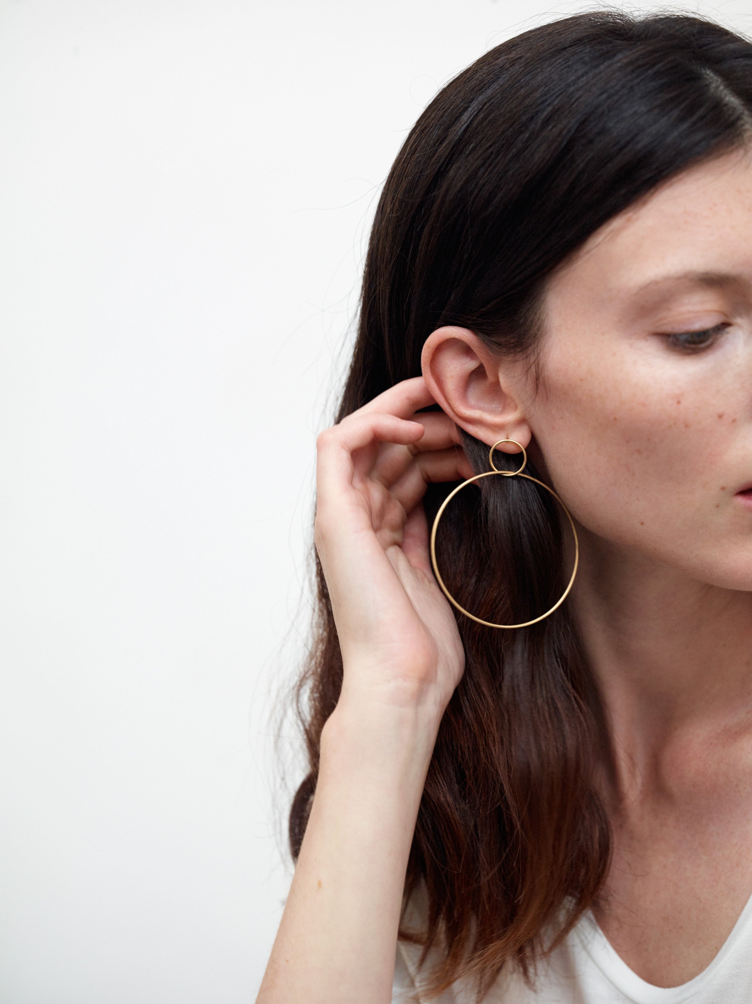 18KT yellow gold large hoop earrings worn by a female ear  - Grande Cerchio