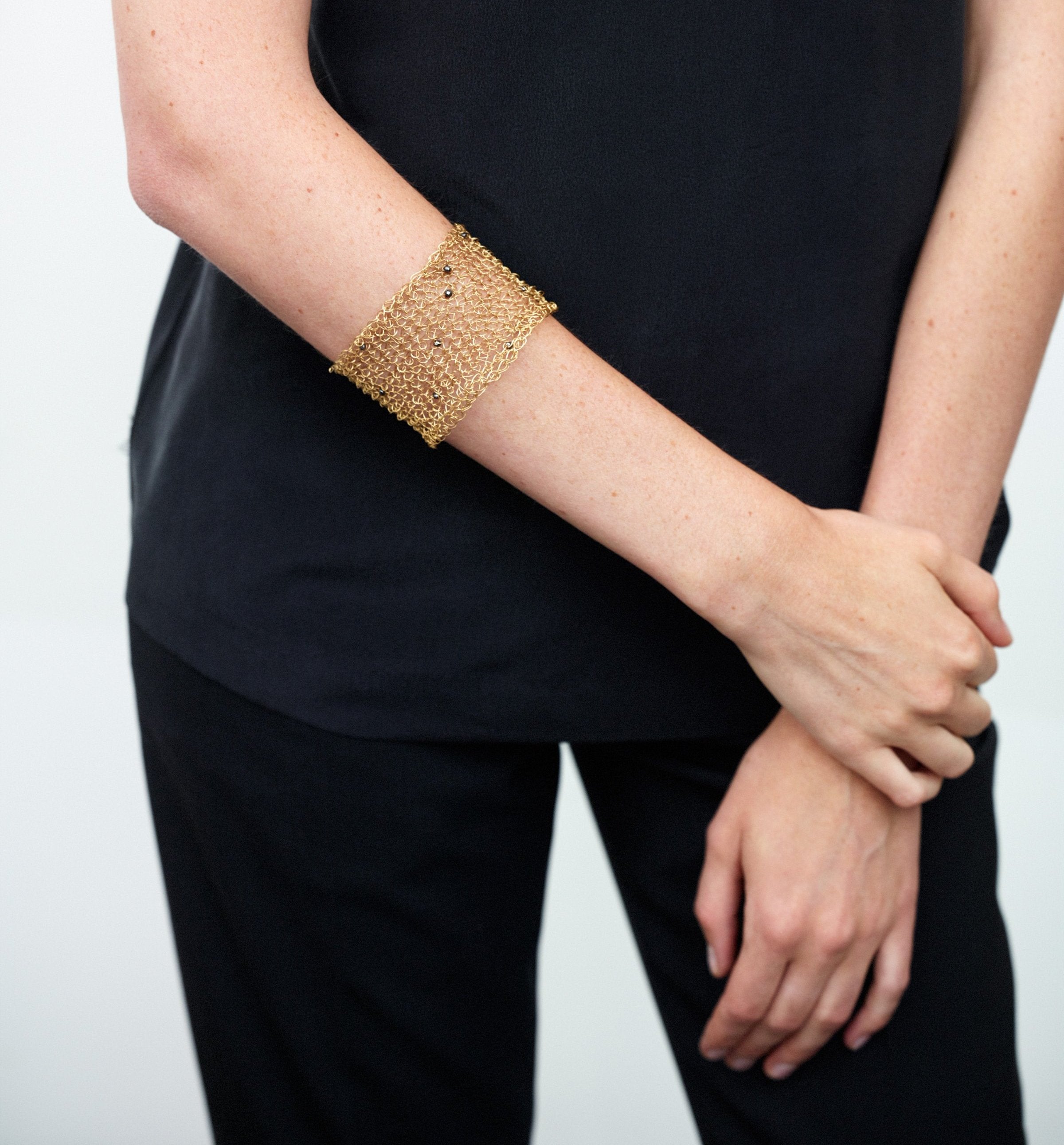 18KT yellow gold cuff bracelet with black spinels worn by female arm - Mesh