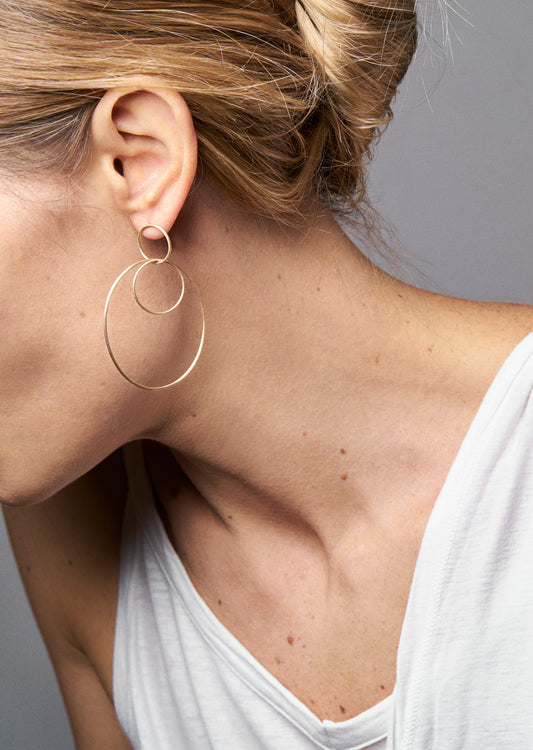 18KT yellow gold large hoop earrings worn by a female ear - Grande Ovale