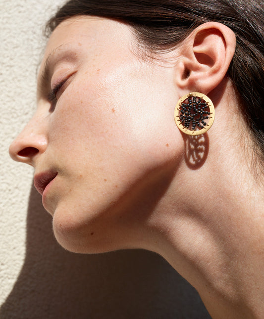 18KT yellow gold stud earrings with black diamonds worn by a female ear  - Round Frame