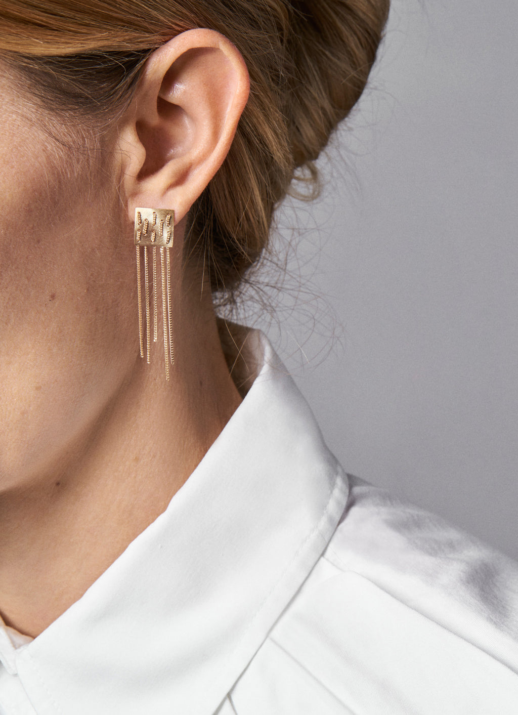 18KT yellow gold chained earrings worn by a female ear - Weave E